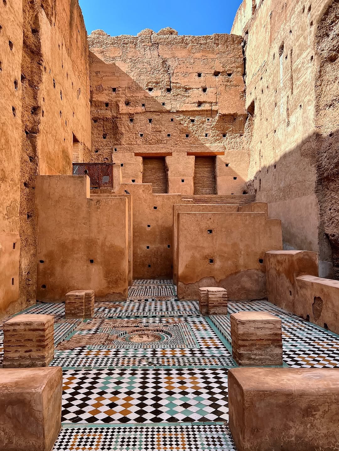 Ruined earthen walls and a zellige mosaic floor inside El Badi Palace in Marrakech