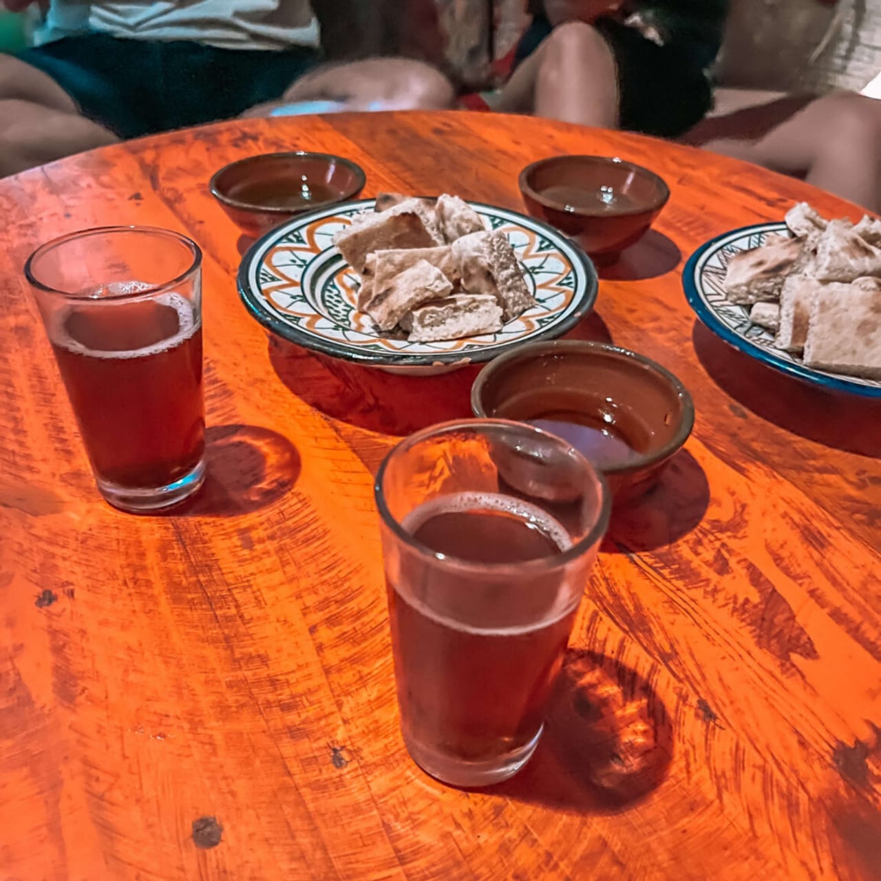 Glasses of Moroccan mint tea and bread on a wooden table under warm evening light